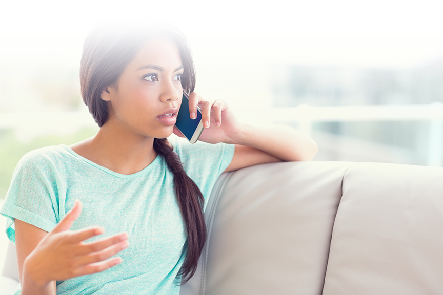 girl sitting on sofa with mobile phone in left hand held up to left ear