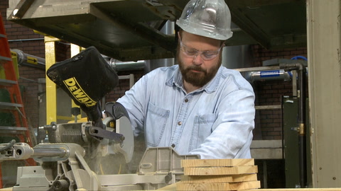 Screen shot of video with a man using a table saw while wearing safety goggles
