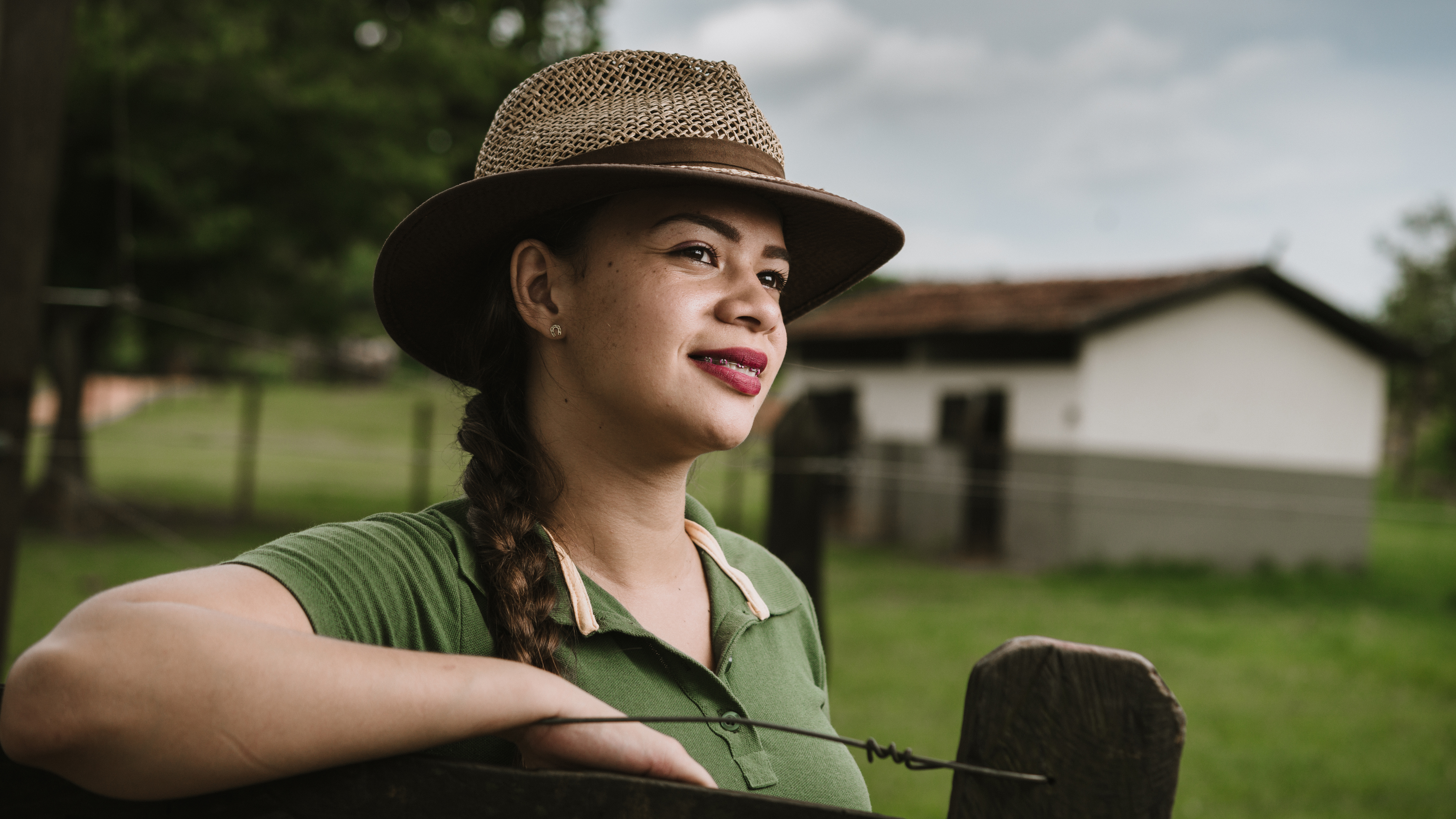 Worker leaning on a fence, a labor housing building in the background.